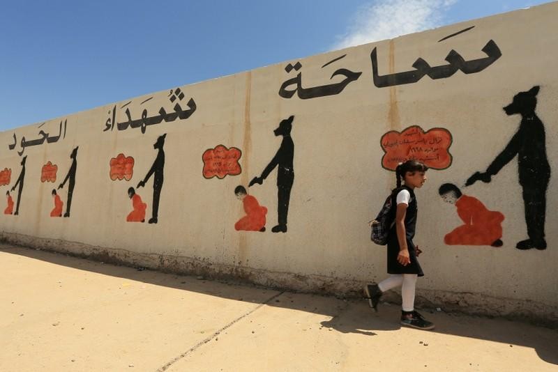 An Iraqi student walks past a school wall covered with drawings showing how Islamic State militants executed their prisoners in Mosul, Iraq April 30, 2018. Photo: REUTERS/Ari Jalal/File Photo